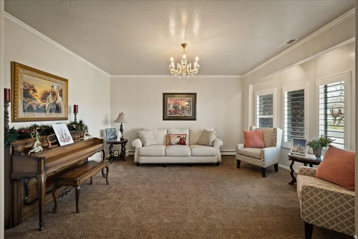 A welcoming front living room features crown molding and plantation shutters.