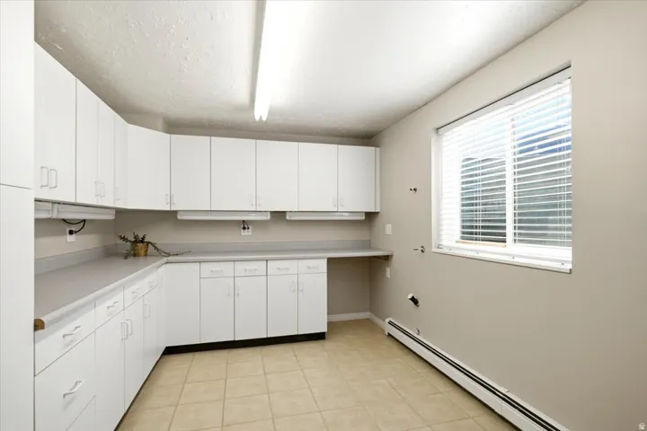 The oversized, remodeled main level laundry room offers abundant cabinetry, a folding counter, a sink, and a built-in ironing board.