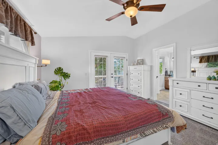 Vaulted ceiling with a ceiling fan, French doors leading to exterior, and an additional doorway to another room