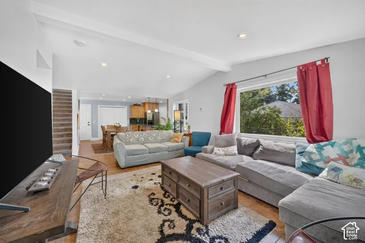 Vaulted ceilings with exposed beams, recessed lighting, and wood-finish flooring throughout