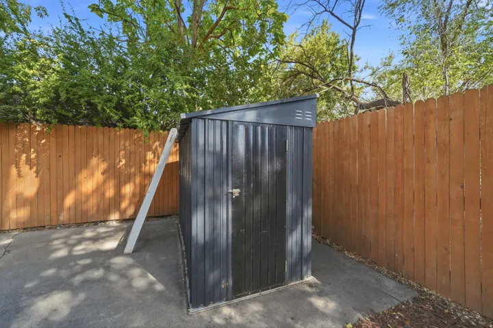 Storage shed with a sloped roof, concrete pad, and wood plank fencing