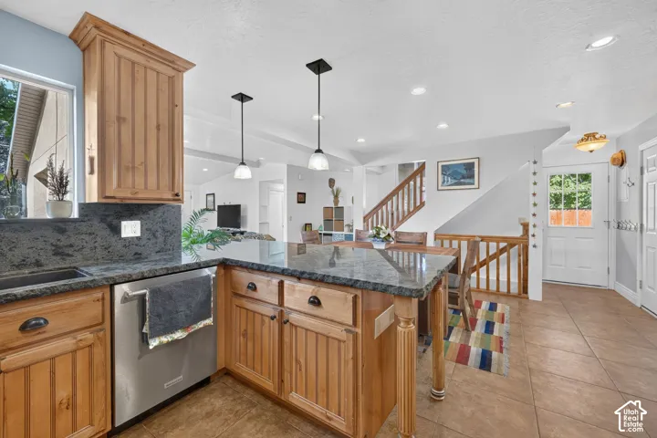 Kitchen island with stone countertop, wood cabinetry, and pendant lighting