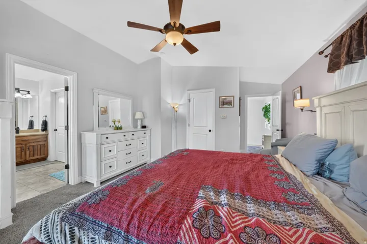 Bedroom featuring a ceiling fan, wall-mounted sconce lighting, and carpet flooring
