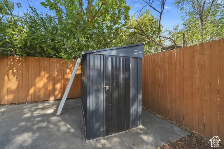 Storage shed with a sloped roof, concrete pad, and wood plank fencing