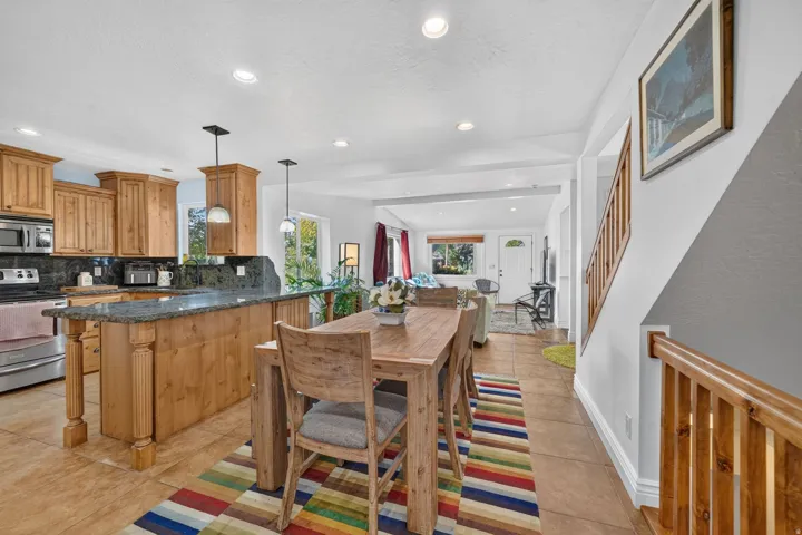 Kitchen with wood cabinetry, stainless steel appliances, and island with stone counter