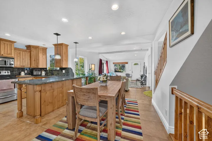 Kitchen with wood cabinetry, stainless steel appliances, and island with stone counter