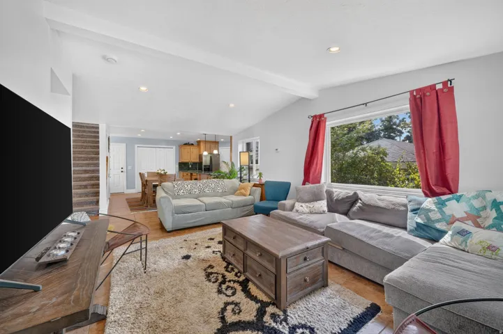 Vaulted ceilings with exposed beams, recessed lighting, and wood-finish flooring throughout