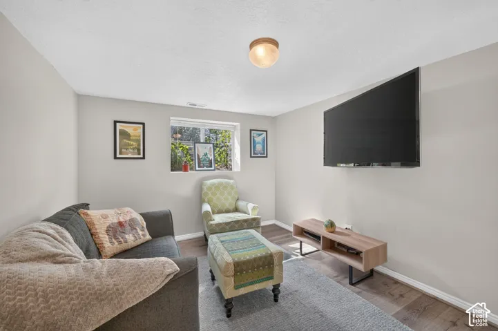 Recessed window with white trim, wood-finish flooring, light grey wall paint, wall-mounted television, and a built-in ceiling light fixture