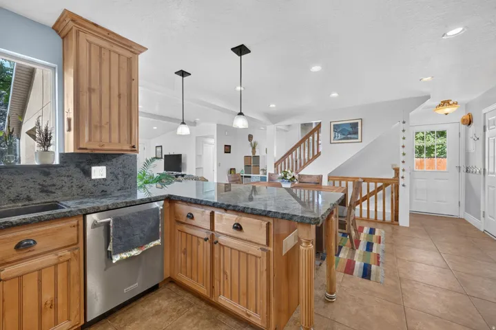 Kitchen island with stone countertop, wood cabinetry, and pendant lighting
