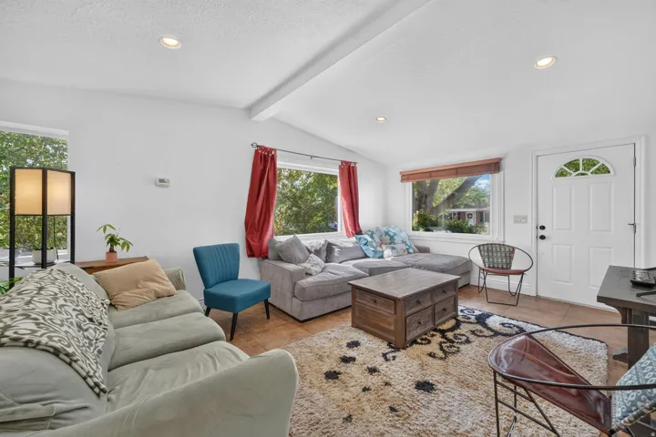 Recessed lighting illuminates the living area with a vaulted ceiling, transom windows, and a panel door with a decorative arch