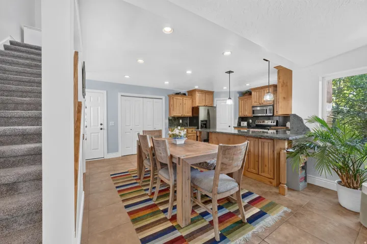 Kitchen with wood cabinetry, dark countertops, tile flooring, and stainless steel appliances