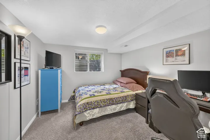 Carpeted flooring, recessed window, ceiling-mounted light fixture, light gray wall paint, and exposed ceiling beams