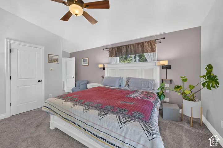 Vaulted ceiling with a ceiling fan, white paneled doors, and grey carpeting
