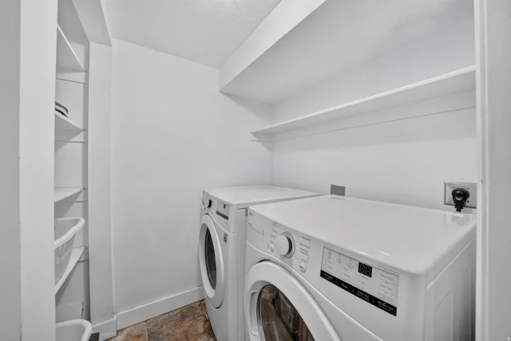Dedicated laundry area with built-in shelving, overhead storage, and tile flooring