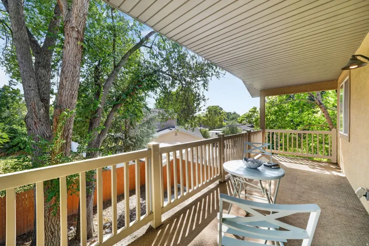 Covered balcony with a slatted ceiling, a light-toned exterior wall, and a wood railing