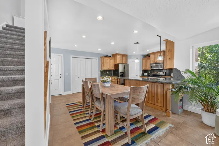 Kitchen with wood cabinetry, dark countertops, tile flooring, and stainless steel appliances