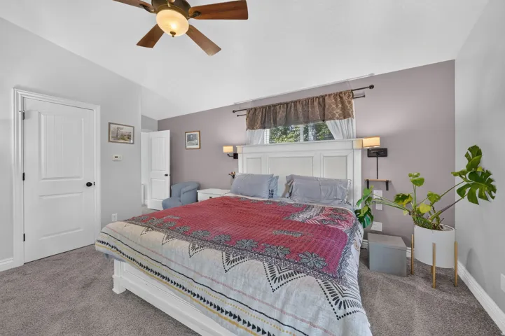 Vaulted ceiling with a ceiling fan, white paneled doors, and grey carpeting