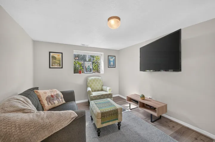 Recessed window with white trim, wood-finish flooring, light grey wall paint, wall-mounted television, and a built-in ceiling light fixture