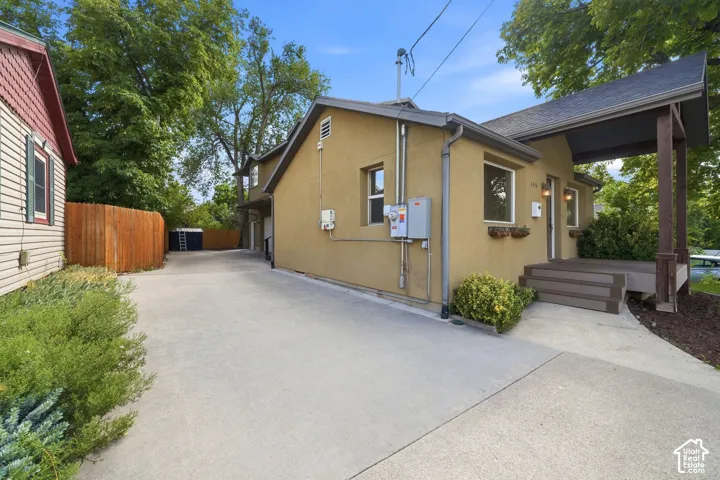 Stucco exterior with a covered front porch, concrete driveway, and wood privacy fencing