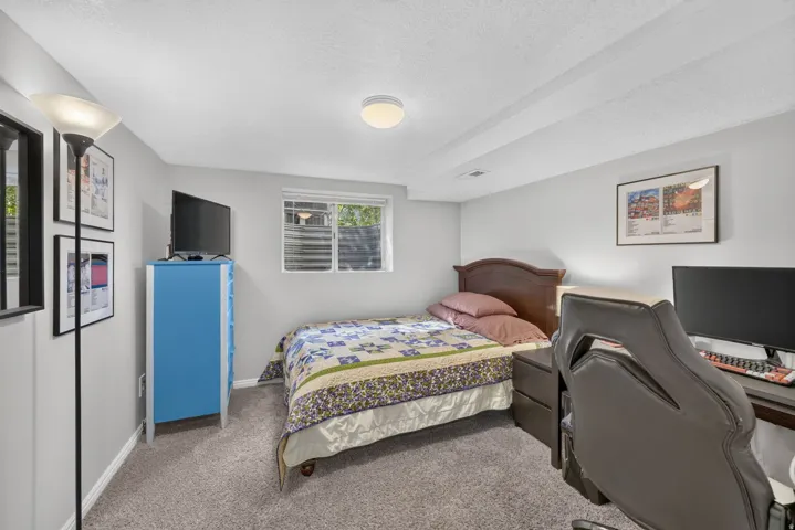 Carpeted flooring, recessed window, ceiling-mounted light fixture, light gray wall paint, and exposed ceiling beams