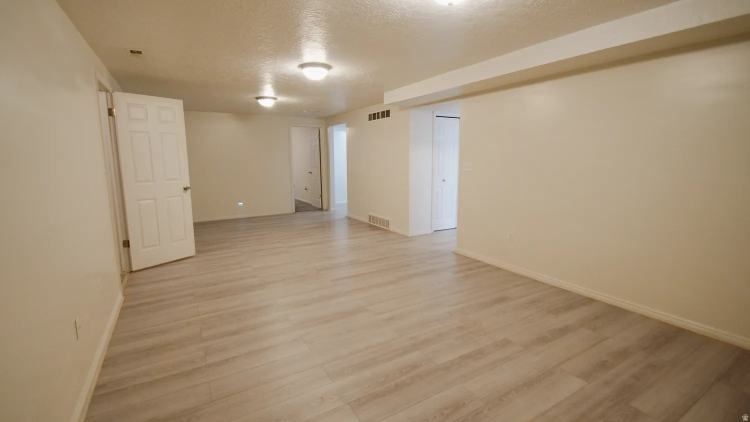 Expansive room featuring wood-finish flooring, recessed lighting, and a neutral color palette