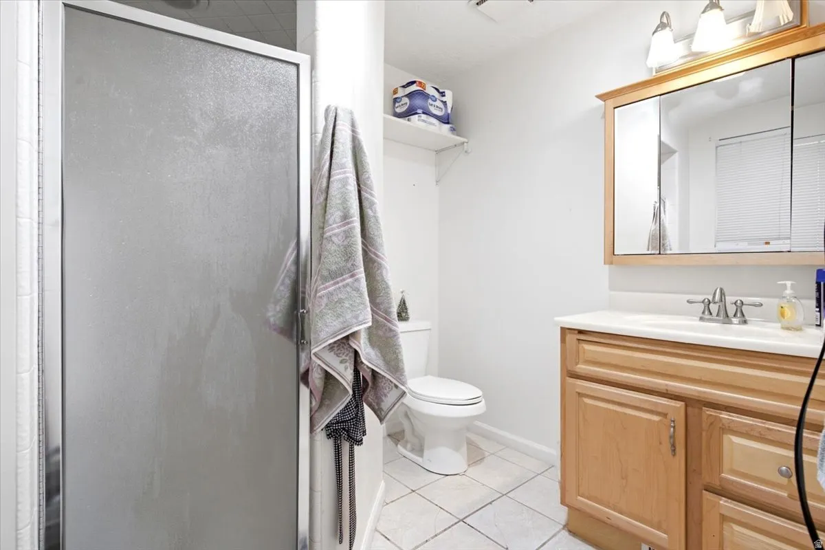 Full bathroom featuring a shower with a framed glass enclosure, ceramic tile flooring, a wood-finish vanity with a built-in sink, and a mirrored medicine cabinet