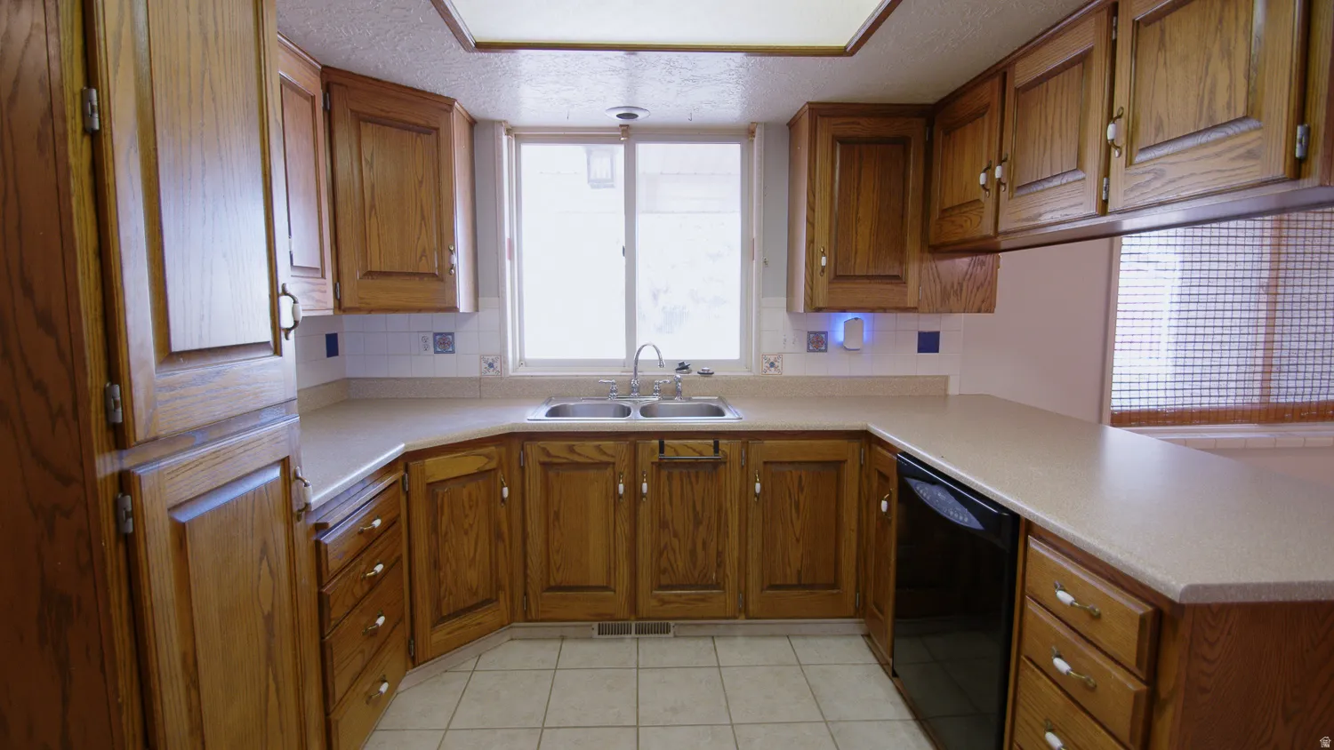 Spacious kitchen featuring warm wood cabinetry, tile flooring, and ample counter workspace