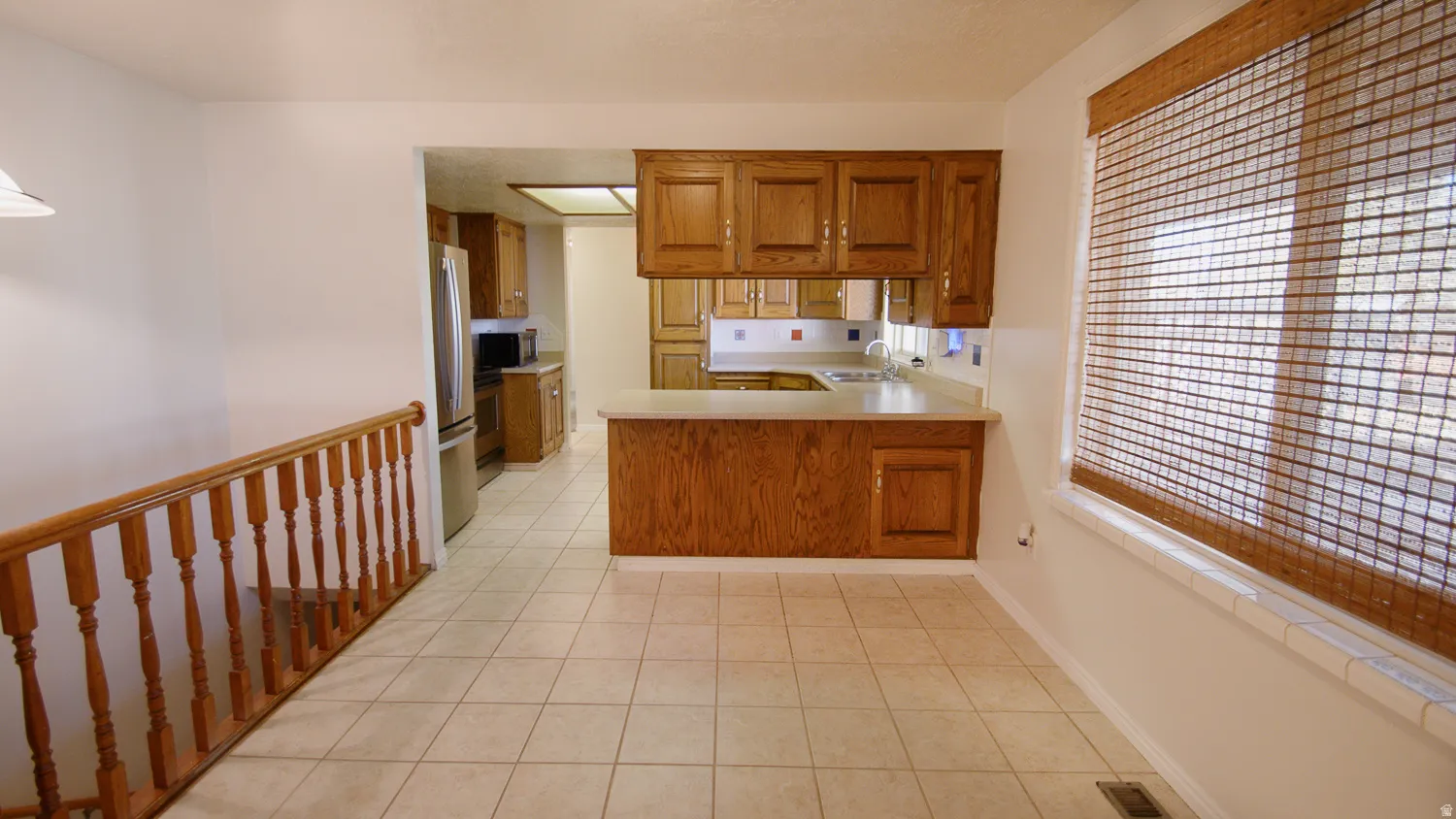Kitchen features wood cabinetry and white countertops