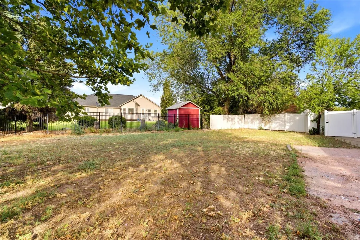 Expansive grounds featuring mature shade trees, a red storage barn, fenced perimeter sections, and a brick-paved driveway