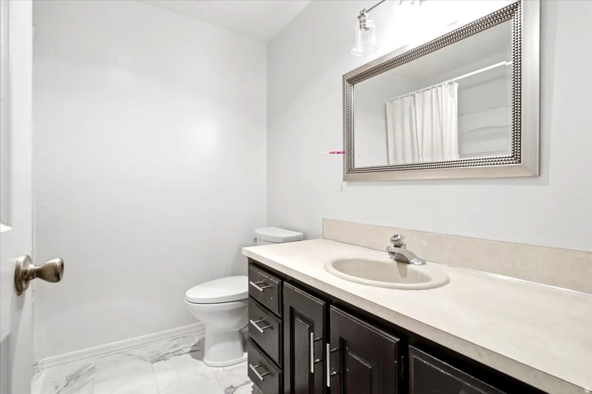 Modern bathroom featuring a dark wood vanity with dual drawers and chrome hardware, white porcelain round sink, cream-colored countertop, and brushed nickel faucet