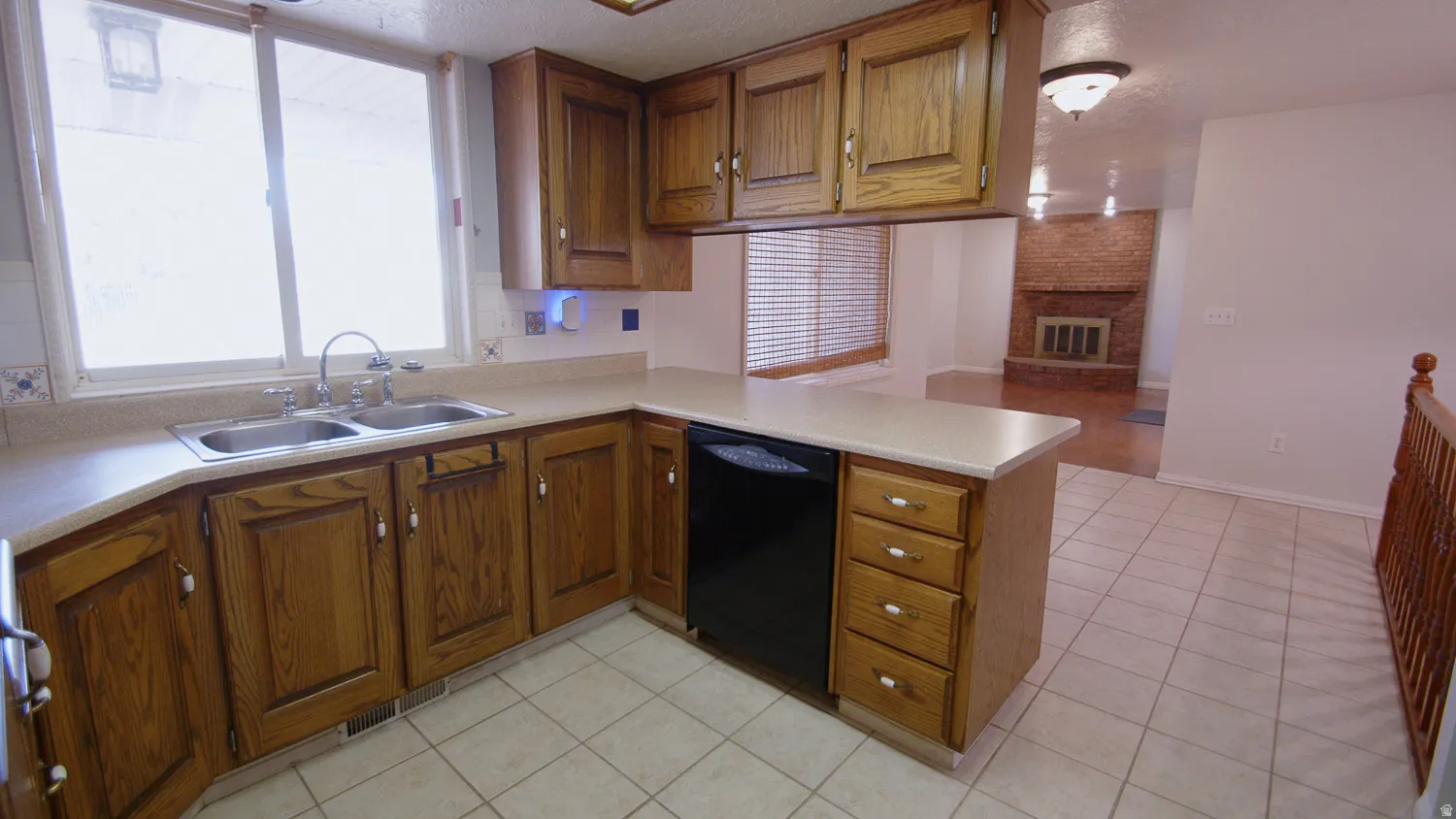 Spacious kitchen featuring warm wood cabinetry, tile flooring, a large center island with storage drawers, and ample counter workspace