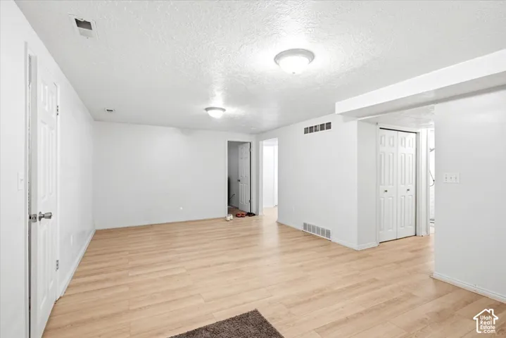 Room featuring wood-finish flooring, white walls, and flush-mount ceiling lighting
