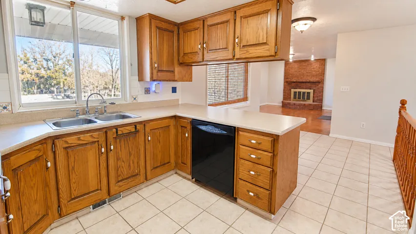 Kitchen with wood cabinetry, light-toned countertops, and a double basin sink