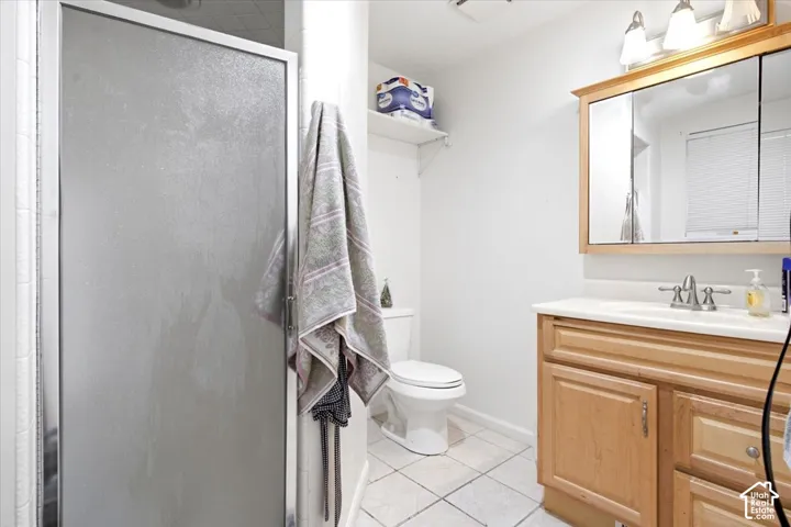 Full bathroom featuring a shower with a framed glass enclosure, ceramic tile flooring, a wood-finish vanity with a built-in sink, and a mirrored medicine cabinet