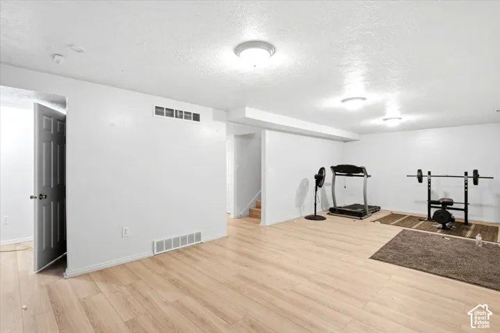 Spacious room featuring wood-finish flooring, white walls, and flush-mount ceiling lighting