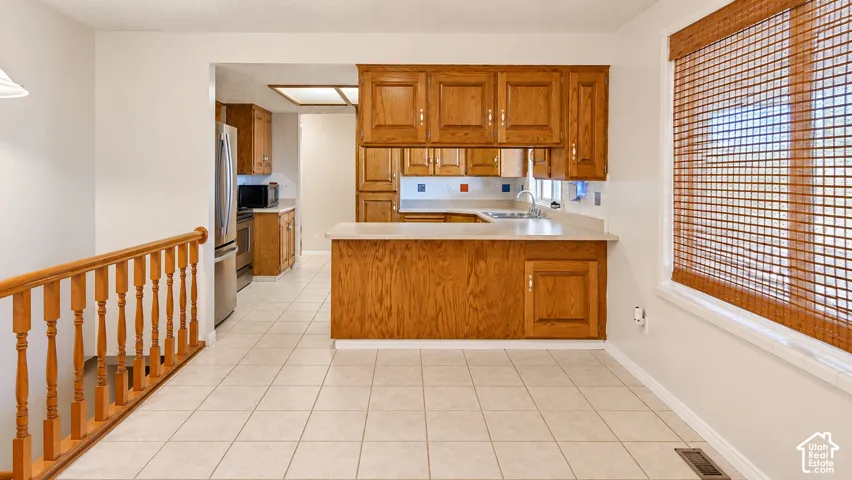 Kitchen featuring wood-finish cabinetry, light-toned countertops, and a stainless steel sink