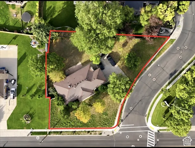 Spacious corner lot featuring mature trees, a multi-gabled roofline, and a paved driveway