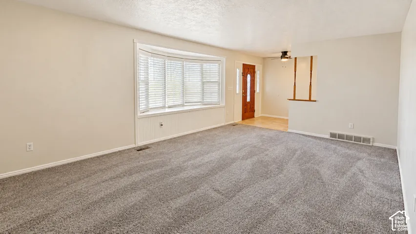 Spacious room with neutral wall tones and textured carpeting