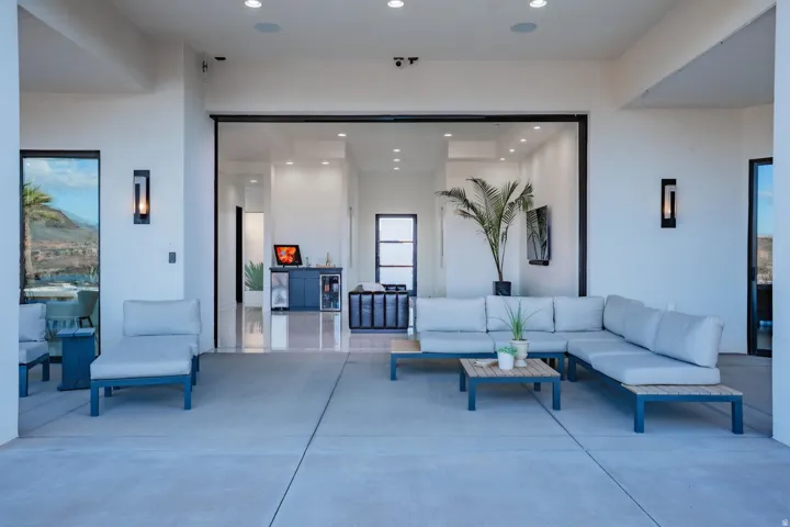 Expansive concrete patio with recessed ceiling lighting, integrated wall sconces, and large sliding glass doors