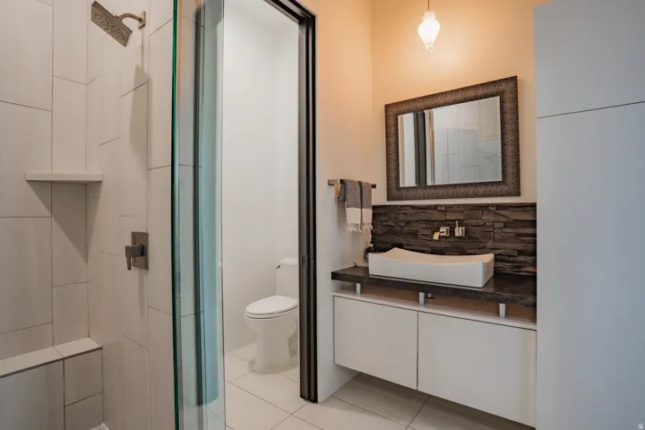 Modern bathroom featuring a walk-in shower with a built-in bench, a glass shower enclosure, a vanity with a vessel sink, and a textured accent wall