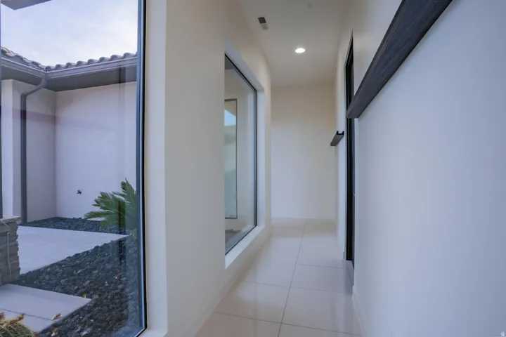 Hallway with recessed lighting, tile flooring, and large fixed windows offering courtyard access