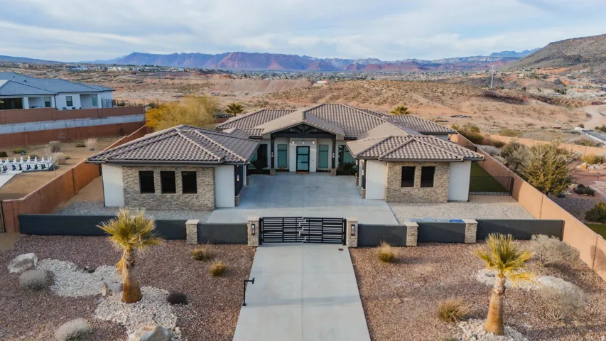 Single-story stucco exterior with stone accents, a tile roof, an integrated drive, and a contemporary entry gate