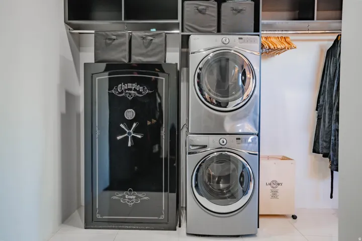 Stacked washer and dryer appliances, custom shelving, and a built-in clothing rod