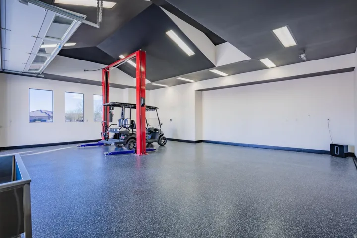 Garage featuring an automotive lift, multiple windows, and a speckled epoxy floor