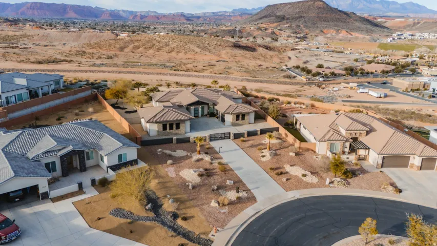 Single-story residence on a cul-de-sac featuring a paved driveway, desert landscaping, and an attached three-car garage