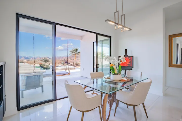 Sleek glass sliding doors, outdoor patio with desert landscaping, contemporary pendant lighting, and polished floor tiles