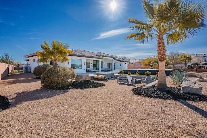 White stucco exterior with a tiled roof, multiple windows, and a large patio area