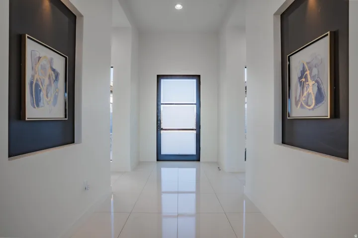 Recessed wall niches with accent lighting, polished tile flooring, and a modern glass-paneled entry door