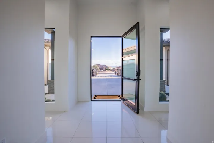 Wide entry featuring a tall pivot door with glass panels, polished tile flooring, and transom-style side windows