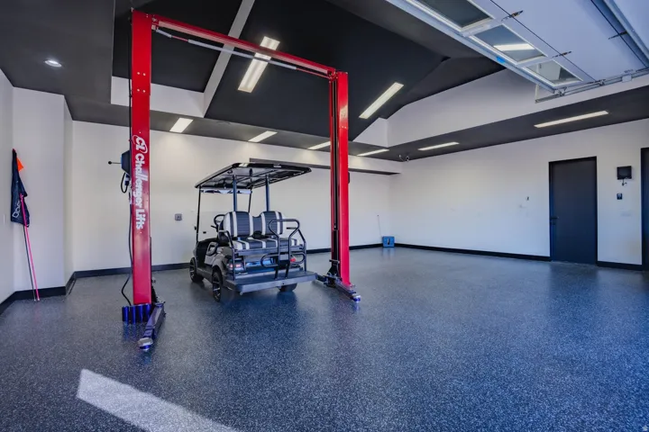Spacious garage featuring a durable epoxy floor, integrated vehicle lift, and recessed ceiling lighting